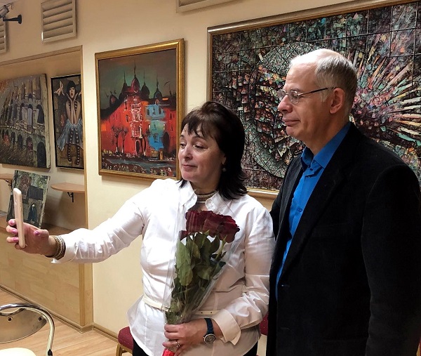 Мария Туманова с гостем выставки на фоне картин  Воввы Морозова